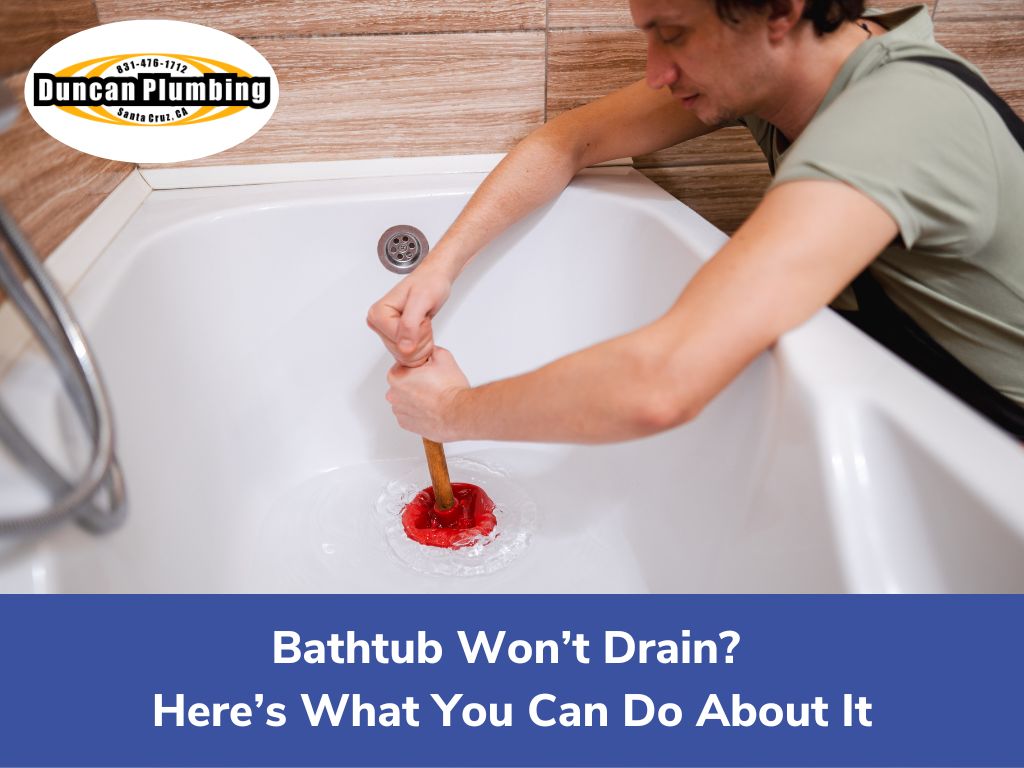 Young plumber in workwear preparing detail for bathtub installation while sitting on squats