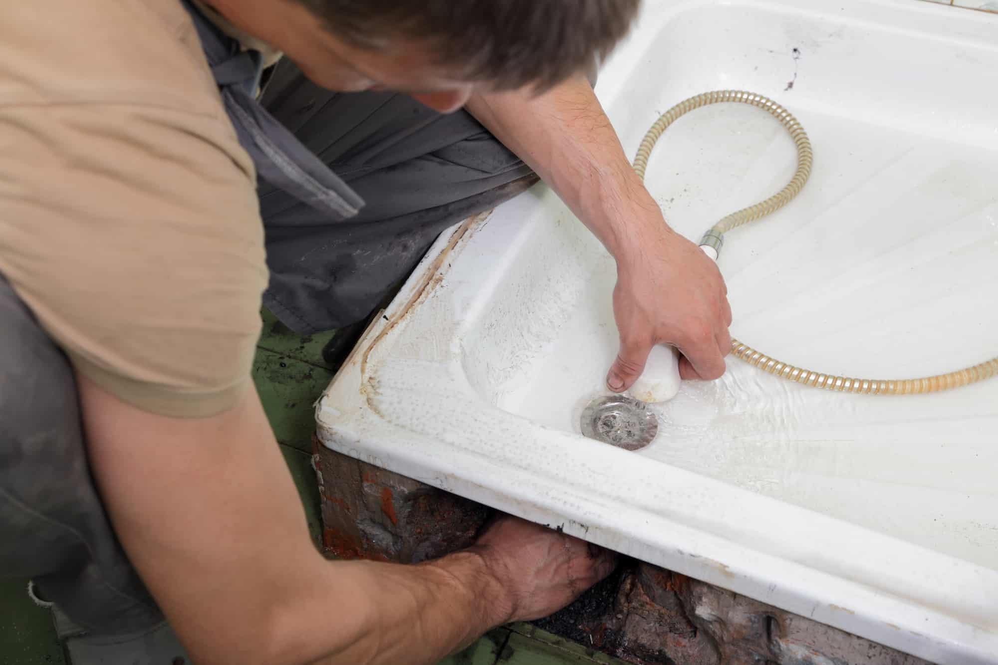 Plumber checking drain in the bathroom with shower